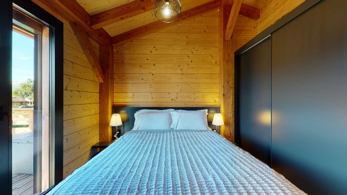 Zimmer mit Bett und blauer Bettwäsche in einem Holzchalet